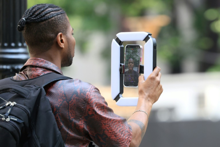 Un homme est en train de se filmer en direct à l'extérieur du tribunal fédéral de Manhattan pendant le procès de P. Diddy (Sean Combs) pour trafic sexuel, à New York, le 6 juin 2025 ( AFP / Charly TRIBALLEAU )