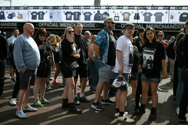 Des fans d'Oasis passent devant la boutique du Principality Stadium à Cardiff le 4 juillet 2025 avant le premier concert de la tournée du groupe emblématique de la Britpop des années 1990 ( AFP / Oli SCARFF )