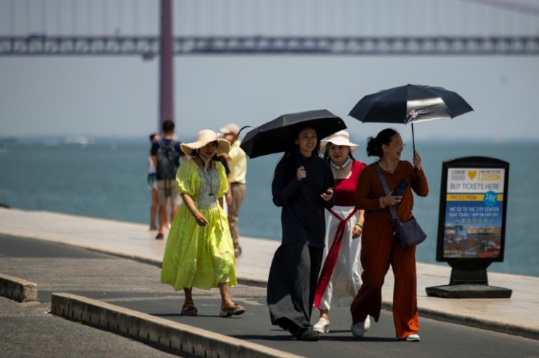 Un groupe de femmes porte des chapeaux et tient des ombrelles pour se protéger du soleil brûlant pendant la première vague de chaleur de l'année à Lisbonne, le 29 juin 2025 ( AFP / CARLOS COSTA )
