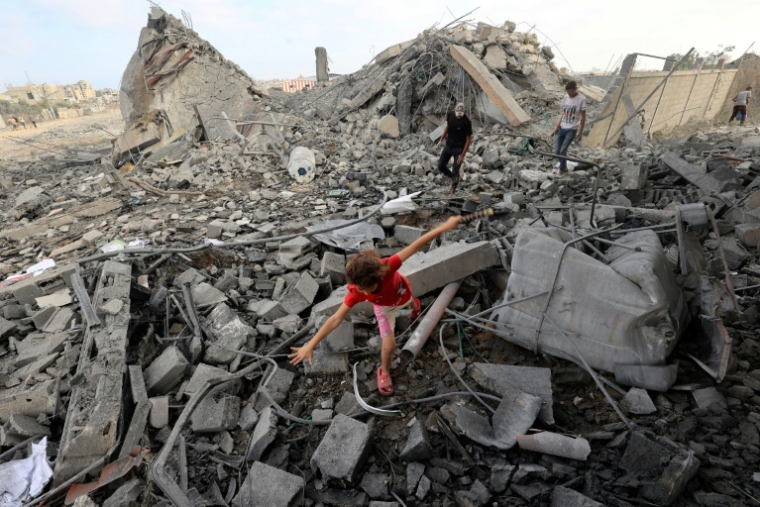 Une fillette palestinienne marche au milieu des décombres d'un bâtiment touché par une frappe israélienne dans le camp de réfugiés de Bureij, dans le centre de la bande de Gaza, le 10 juillet 2025 ( AFP / Eyad BABA )