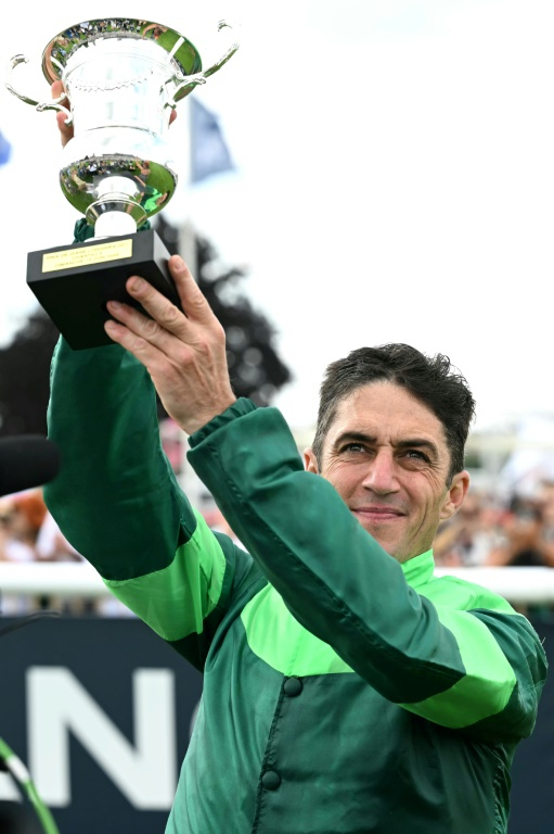 Le Belge Christophe Soumillon brandit son trophée après avoir remporté le Prix de Diane, le 15 juin 2025 à Chantilly, dans l'Oise ( AFP / Hugo MATHY )