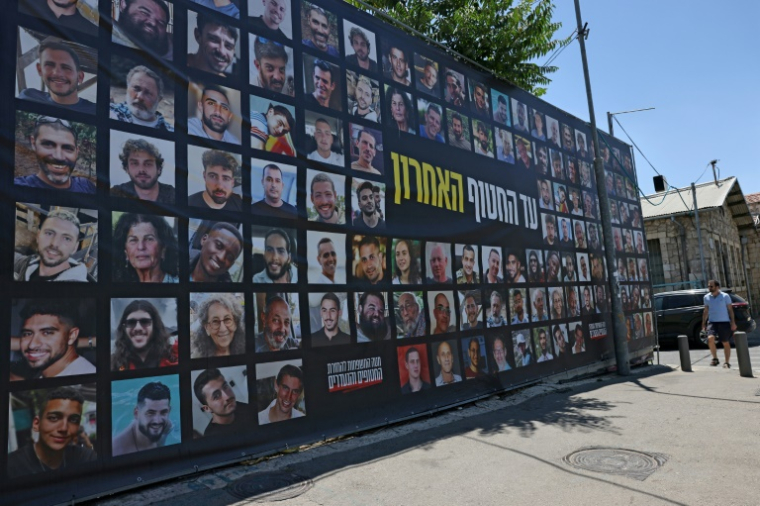Un homme passe devant un panneau à Jérusalem sur lequel sont affichés les portraits des otages israéliens retenus à Gaza, le 4 juillet 2025 ( AFP / AHMAD GHARABLI )