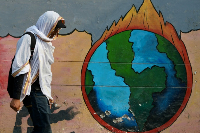 Un passant marche devant une peinture murale en pleine vague de chaleur à Varanasi, en Inde, le 9 juin 2025 ( AFP / Niharika KULKARNI )