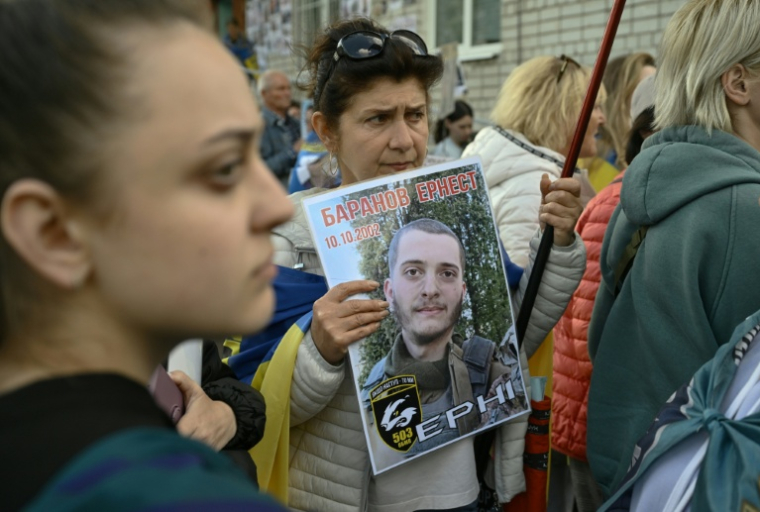Elmira Baranova tient un portrait de son fils disparu Ernest, en attendant l'arrivée de prisonniers de guerre ukrainiens libérés après un échange avec la Russie, dans la région de Tcherniguiv (Ukraine), le 26 juin 2025 ( AFP / Genya SAVILOV )