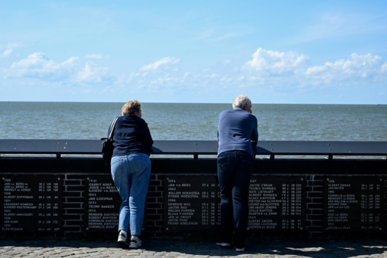 Des visiteurs à côté de plaques portant les noms de pêcheurs disparus en mer à Urk, le 3 juillet 2025 aux Pays-Bas ( AFP / Nicolas TUCAT )