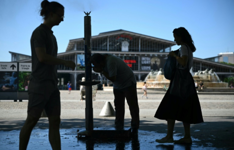 Des personnes se rafraîchissent à une fontaine publique près de la Grande Halle de La Villette alors qu'une vague de chaleur frappe le sud de l'Europe, à Paris, le 29 juin 2025 ( AFP / Julie SEBADELHA )