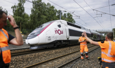 Un TGV Inoui passe près de techniciens de la SNCF qui travaillent à reconnecter les câbles ferroviaires à la gare de Mont-de-Terre à Lille, le 25 juin 2025 dans le Nord ( AFP / Sameer Al-DOUMY )