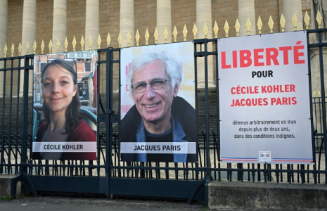Les photos de Cécile Kohler et Jacques Paris sur les grilles de l'Assemblée nationale à Paris le 25 mars 2025 ( AFP / BERTRAND GUAY )