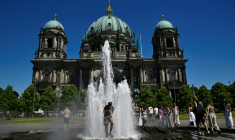 Des personnes se rafraîchissent dans l'eau d'une fontaine, le 2 juillet 2025 à Berlin ( AFP / John MACDOUGALL )
