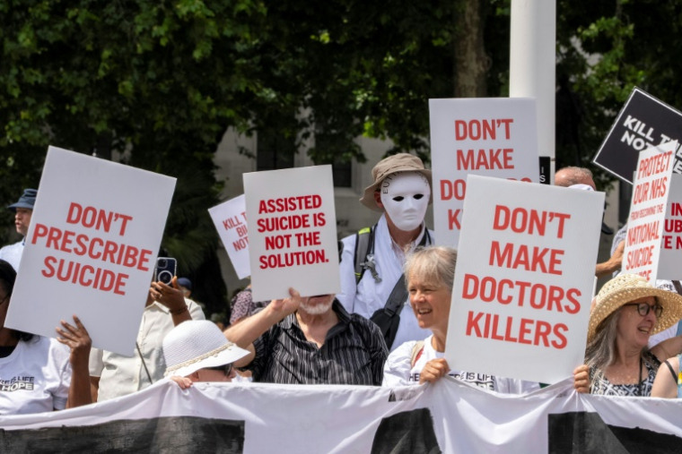 Des manifestants opposés à une modification de la loi sur l'aide médicale à mourir rassemblés devant le Palais de Westminster, le 20 juin 2025 à Londres, alors que les députés doivent voter sur l'opportunité d'autoriser l'aide  à mourir pour certains malades en phase terminale ( AFP / CARLOS JASSO )