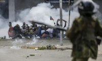 Des manifestants se mettent à couvert alors que la police tire des gaz lacrymogènes, le 25 juin 2025 à Nairobi, au Kenya ( AFP / SIMON MAINA )