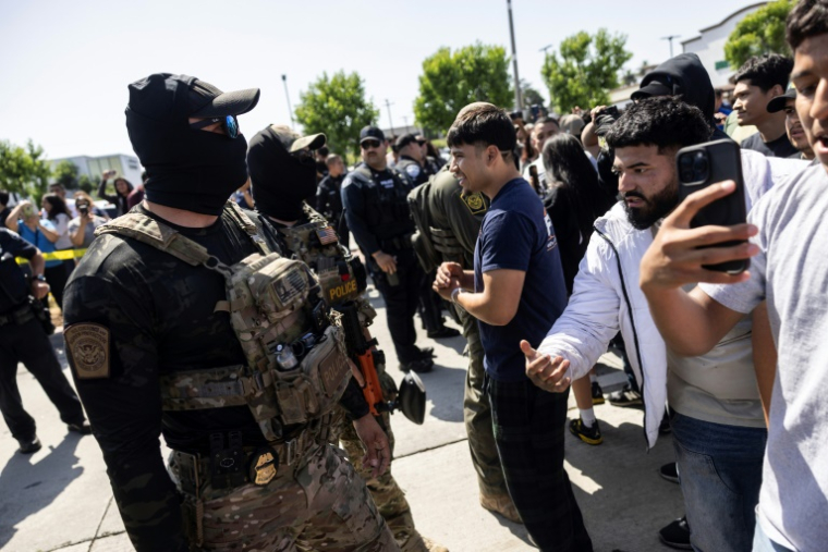 Des passants protestent et filment les agents fédéraux impliqués dans l'arrestation d'un homme à Bell, une banlieue de Los Angeles où la population est majoritairement latino-américaine, le 20 juin 2025 ( AFP / ETIENNE LAURENT )