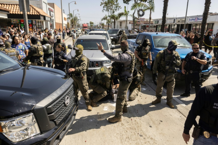 Une foule entoure des agents fédéraux pendant l'arrestation d'un homme à Bell, une banlieue de Los Angeles où la population est majoritairement latino-américaine, le 20 juin 2025 ( AFP / ETIENNE LAURENT )