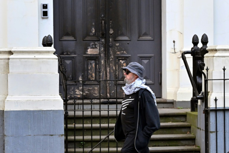 Un homme passe devant la porte principale d'une synagogue de Melbourne partiellement incendiée, le 6 juillet 2025 ( AFP / William WEST )
