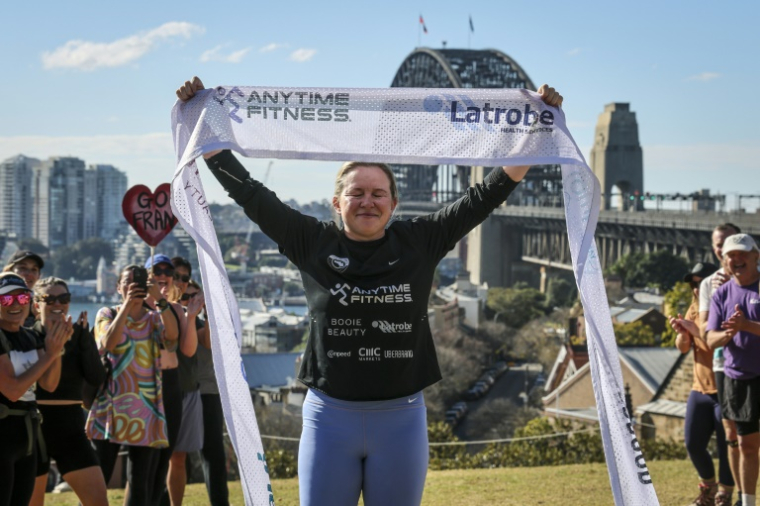 L'ex-footballeuse britannique Fran Hurndall entourée de supporteurs après avoir bouclé une course de charité de 3.800 kilomètres à travers l'Australie, le 29 juin 2025 à Sydney ( AFP / DAVID GRAY )