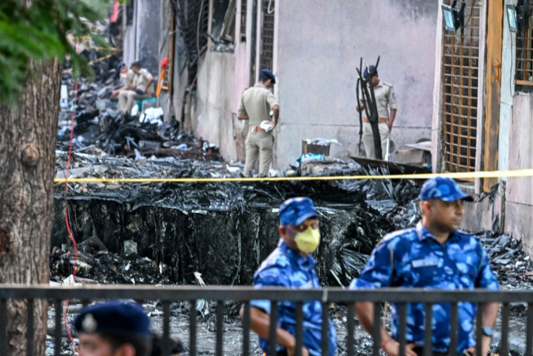 Des policiers montent la garde sur le site du crash du vol 171 d'Air India dans un quartier résidentiel près de l'aéroport d'Ahmedabad, le 13 juin 2025 en Inde ( AFP / Punit PARANJPE )
