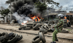 Un policier kényan déplace des pneus bloquant un axe routier, le 7 juillet 2025 à Nairobi ( AFP / Luis TATO )