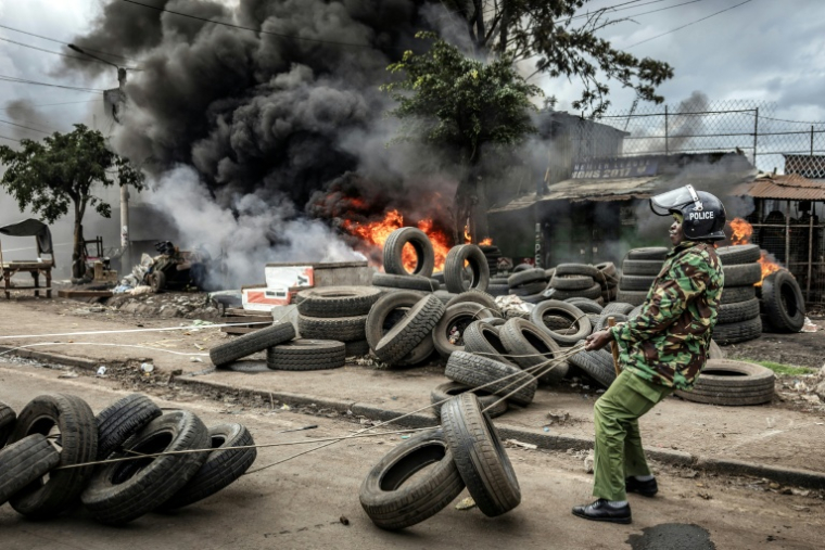 Un policier kényan déplace des pneus bloquant un axe routier, le 7 juillet 2025 à Nairobi ( AFP / Luis TATO )