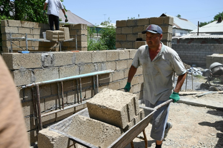 Des ouvriers construisent une maison avec des parpaings en riz, dans le village de Kyzyl-Kiya, dans le sud du Kirghizistan, le 22 mai 2025 ( AFP / Guliza Urustambek kyzy )