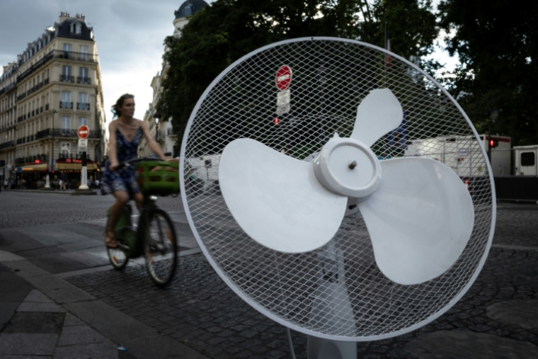 Une cycliste circule près d'un ventilateur abandonné, le 27 juin 2025 à Paris ( AFP / JOEL SAGET )